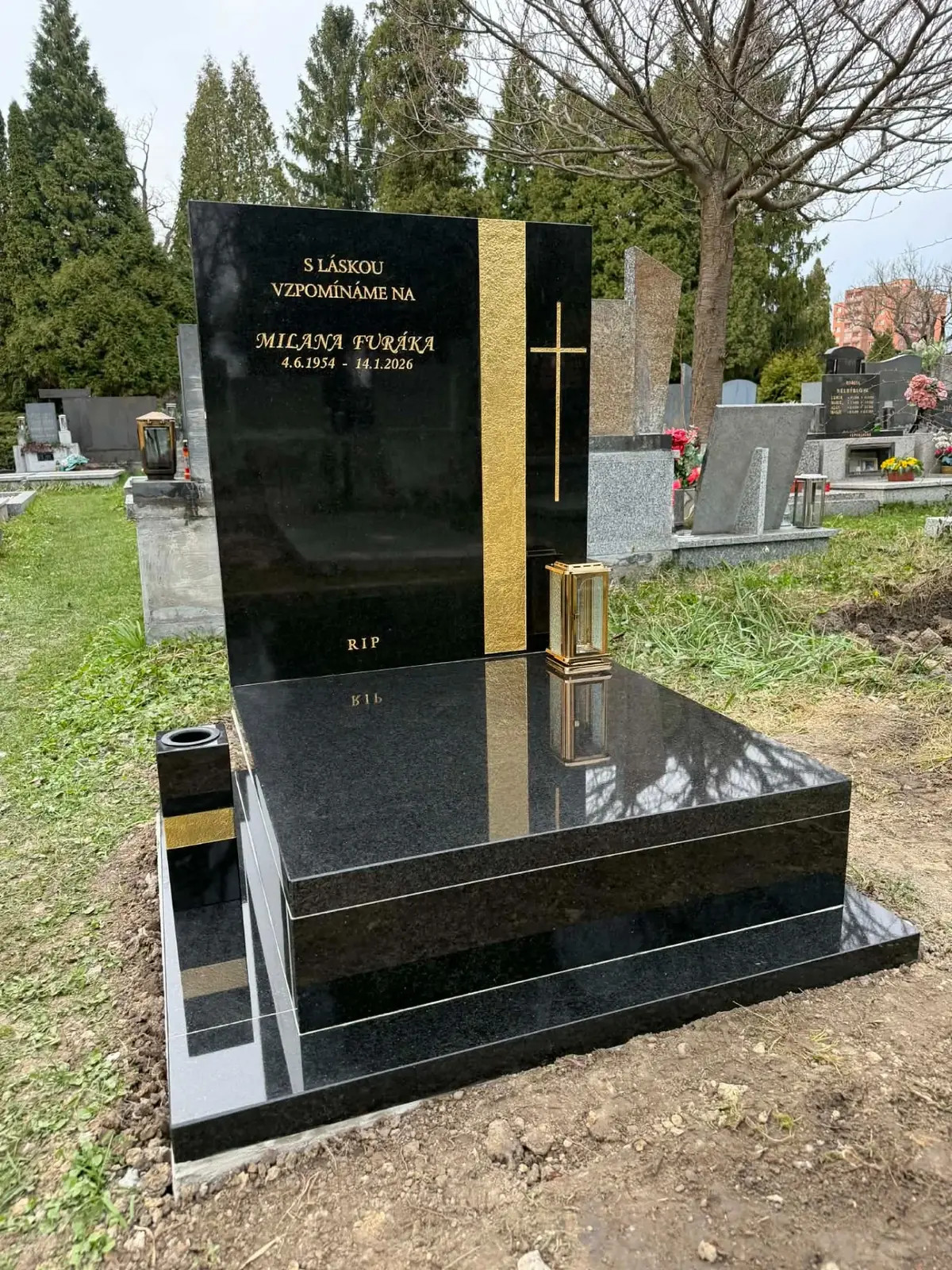 Moderní urnový hrob z černé žuly se zlatým pruhem a křížem